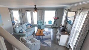 A spacious living room with a sofa, armchairs, a coffee table, and a ceiling fan. - Beach “N” Bay Getaway Sleeps 9. Enjoy Beach Time,  Fishing, Kayaking. Steps Away (Gulf Shores)