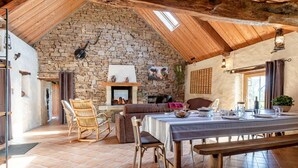 Ein rustikaler Essbereich mit Steinwand, Holzbalkendecke und Kamin.