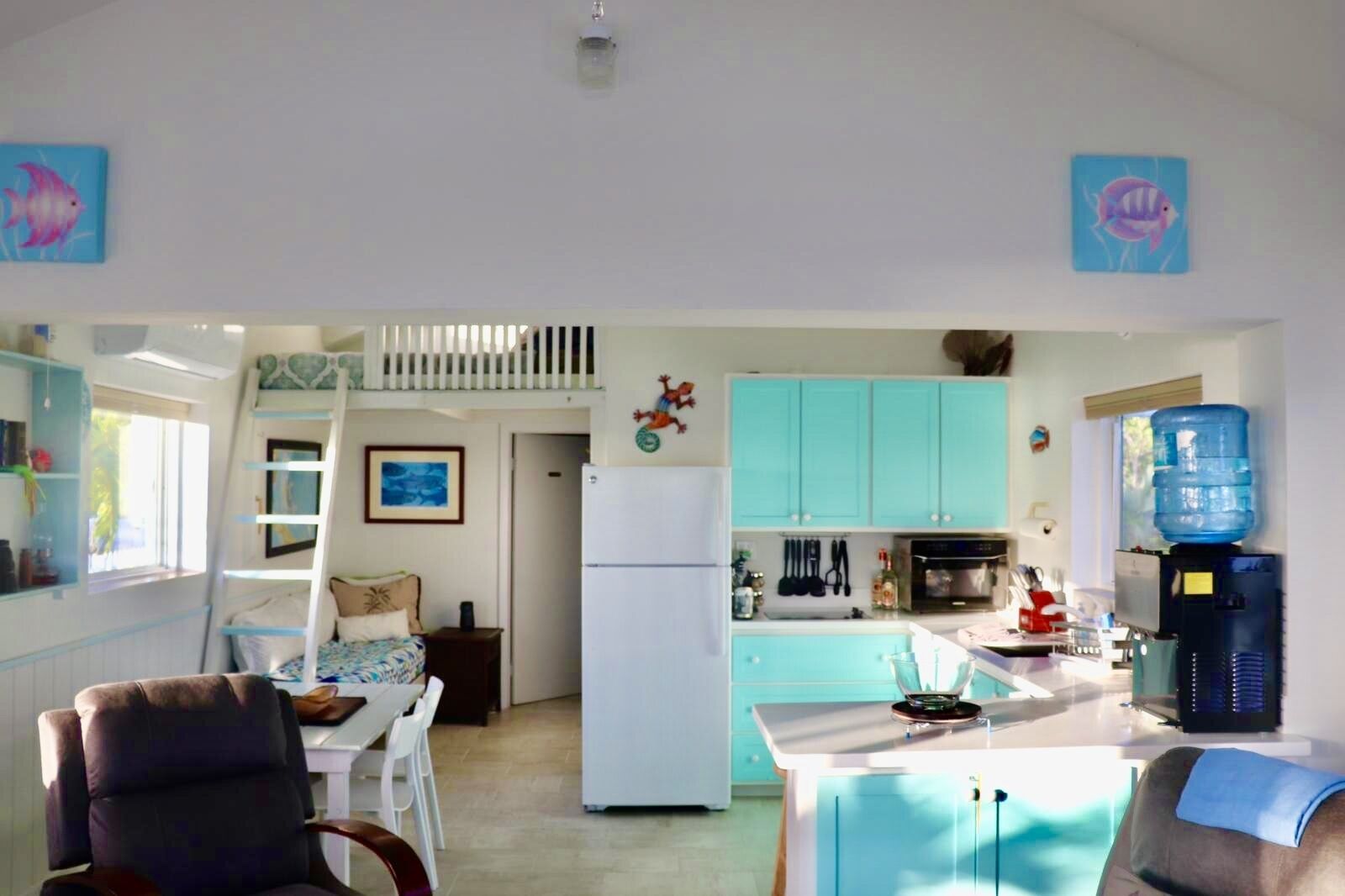 Un espace de vie compact comprenant un coin cuisine, un coin repas et une petite chambre avec un lit superposé.