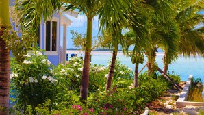 A coastal view with a building, palm trees, and a beach. - Amazing Beachfront home the calm side of the island. Swimming & kayaking (Exuma)