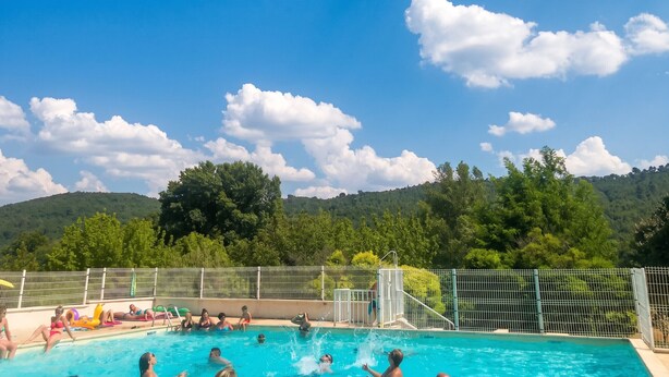 A swimming pool with people enjoying the water, surrounded by a fence and trees. - Homerez - House in Saint-Martin-de-Brômes (Saint-Martin-de-Brômes)