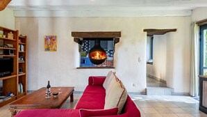 Una sala de estar con un sofá rojo, una mesa de centro de madera y una chimenea.
