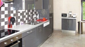 Una cocina moderna con gabinetes grises, una encimera negra y un lavamanos de acero inoxidable.