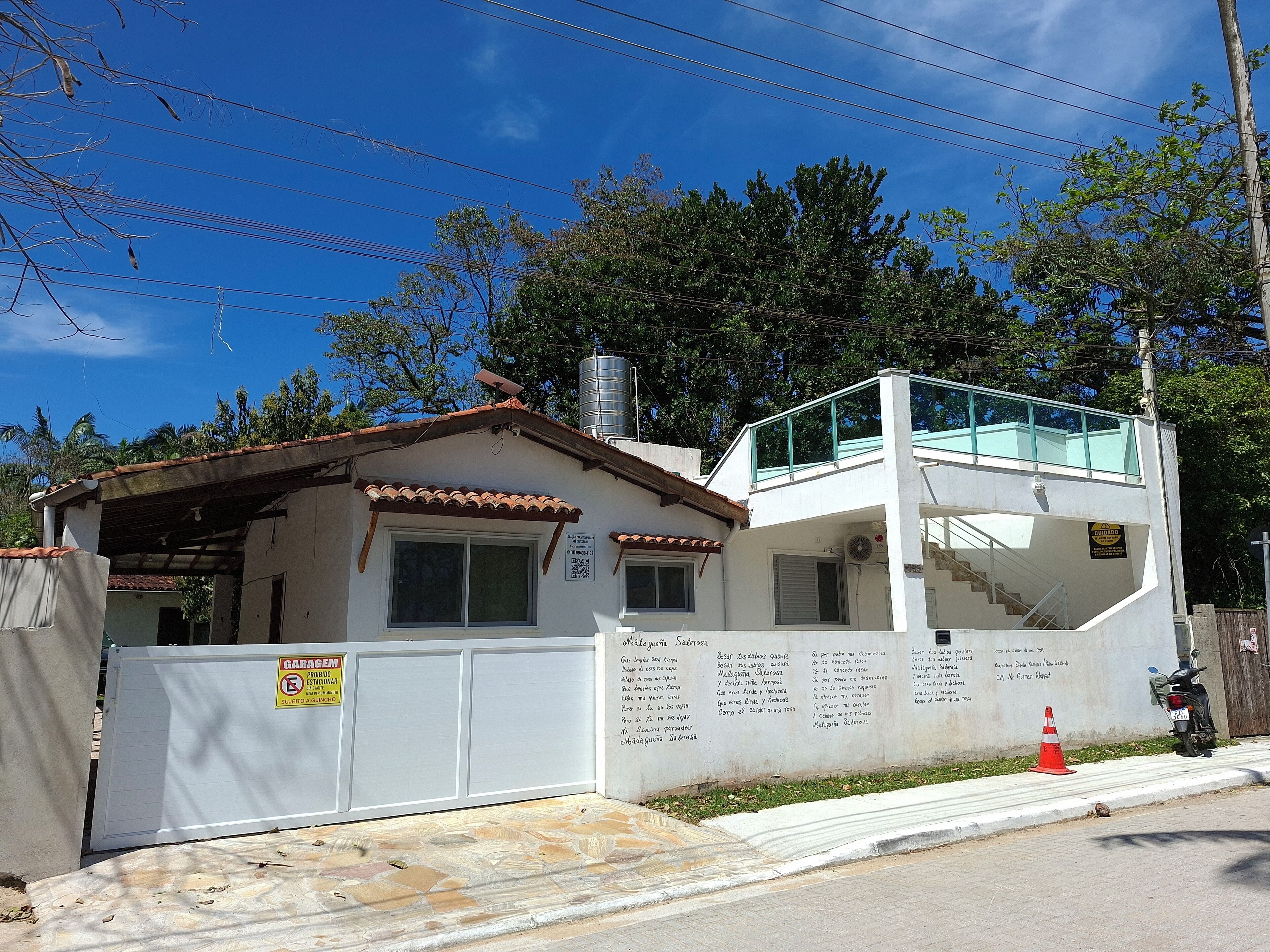 A two-story building with a balcony, a garage, and a wall with text.