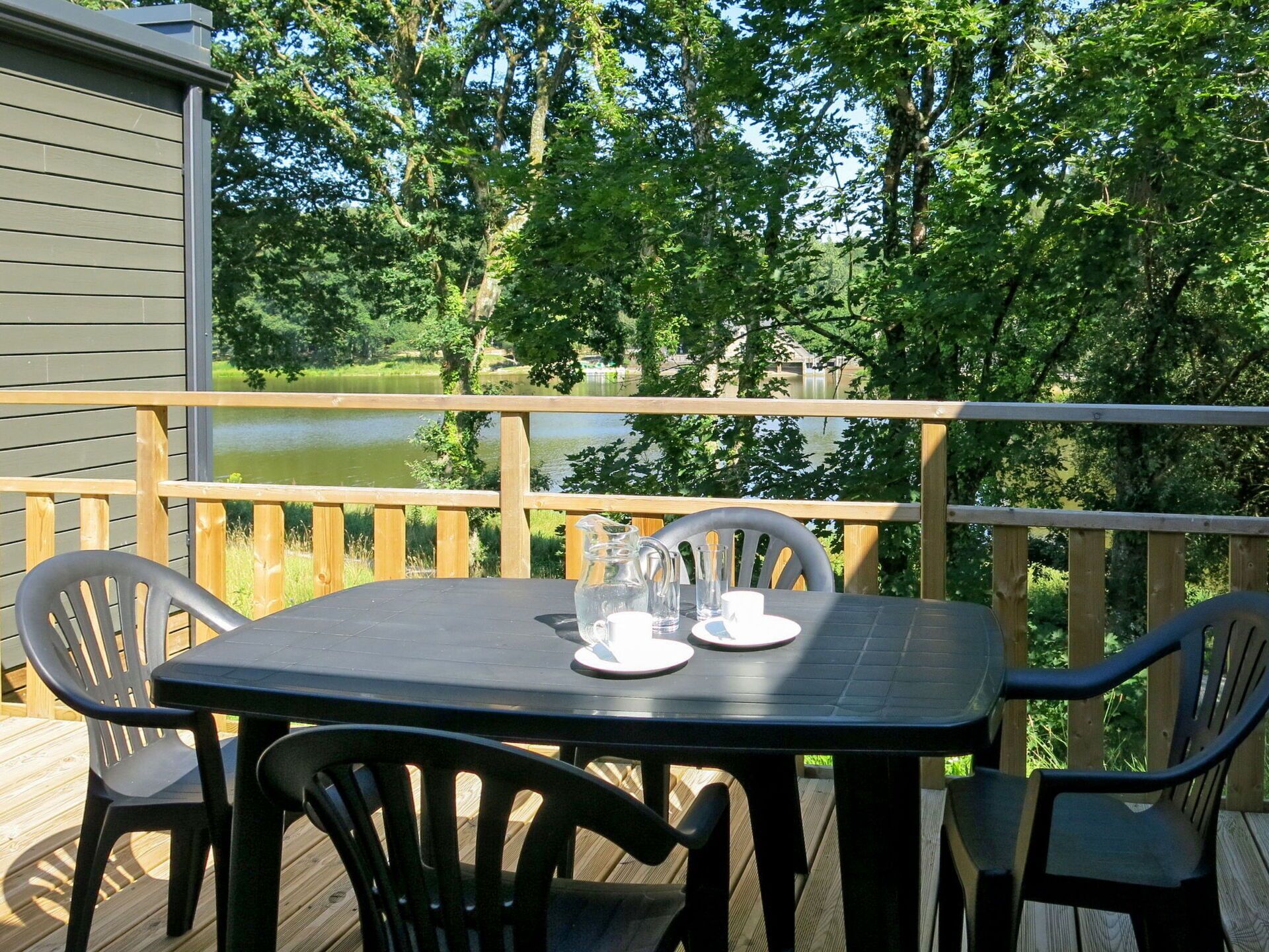 A deck with a table and chairs overlooking a lake.
