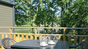 A deck with a table and chairs overlooking a lake. - Nice apartment in villa for 6 people with WIFI, pool, TV, terrace and pets allowed (Rochefort-en-terre)