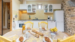 Una cocina con pared de piedra, una mesa de comedor con cosas para el desayuno y vistas al área de estar.