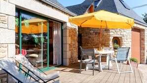 Un patio con una mesa y sillas, una tumbona y un paraguas amarillo.