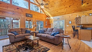 A cozy cabin interior with two sofas, a coffee table, and a dining area. - Mountaintop Getaway with Gazeebo Deck Hot Tub & Fireplace! Long range views! (Bryson City)