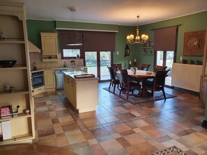 Una cocina con comedor, que incluye una isla central, armarios de madera y una araña.
