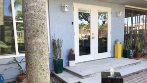 A house with a concrete porch, potted plants, and a stone sculpture. - Quiet cozy home near Anna Maria Island, Robinson Preserve, DeSoto Nt’l Monument (Bradenton)