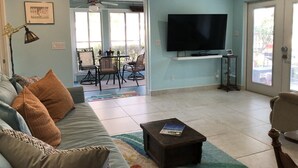 A living room with a sofa, coffee table, and a TV. There is a dining area with chairs and a table. - Quiet cozy home near Anna Maria Island, Robinson Preserve, DeSoto Nt’l Monument (Bradenton)