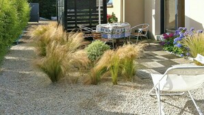 Um pátio com mesa e cadeiras, cercado por cascalho e plantas.