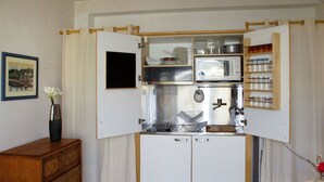Cozinha compacta com micro-ondas, fogão e armários.