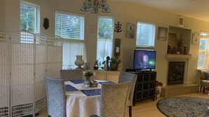 A cozy living room with a dining area, a fireplace, and a television. - Lovely 2 bedroom craftsman style home (Lincoln Beach)