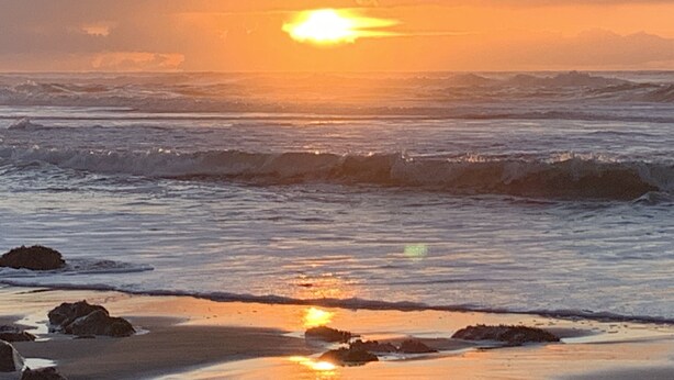 A beach scene with waves and a sunset. - Lovely 2 bedroom craftsman style home (Lincoln Beach)