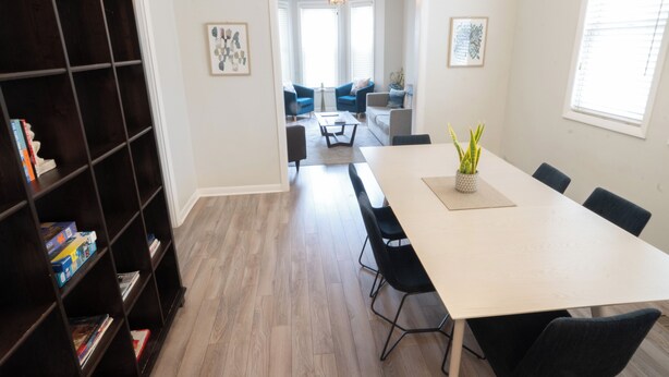 Una sala moderna con una mesa de comedor, sillas, una estantería y vistas al área de estar contigua.