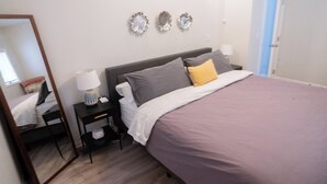 Un dormitorio con una cama, una mesita de noche, una lámpara, un espejo y adornos en la pared.