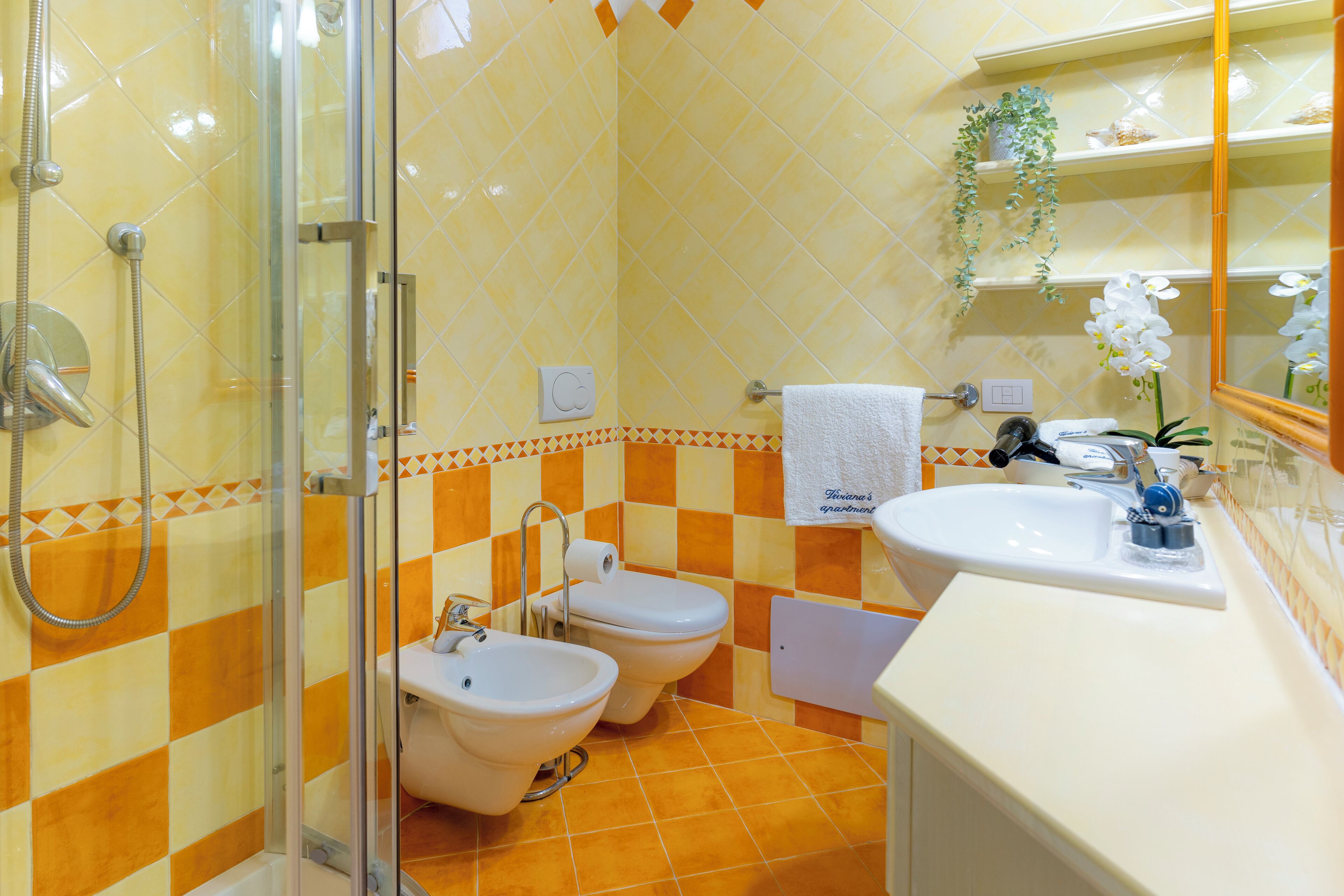 Une salle de bain avec une douche à parois de verre, deux toilettes, un bidet et un lavabo.