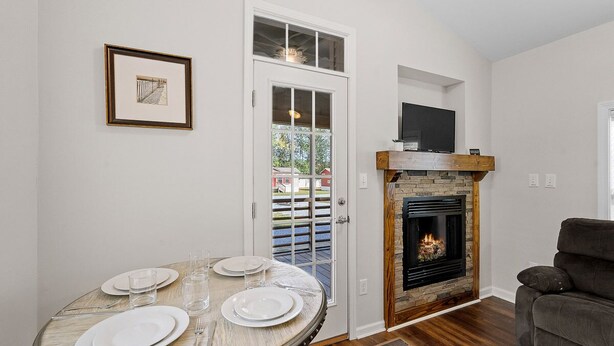 Un comedor con una mesa redonda dispuesta para cuatro personas, una chimenea y un televisor montado encima.