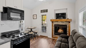 Una cocina moderna con estufa a gas, microondas y horno, un comedor con mesa redonda y sillas, chimenea y ventilador de techo.