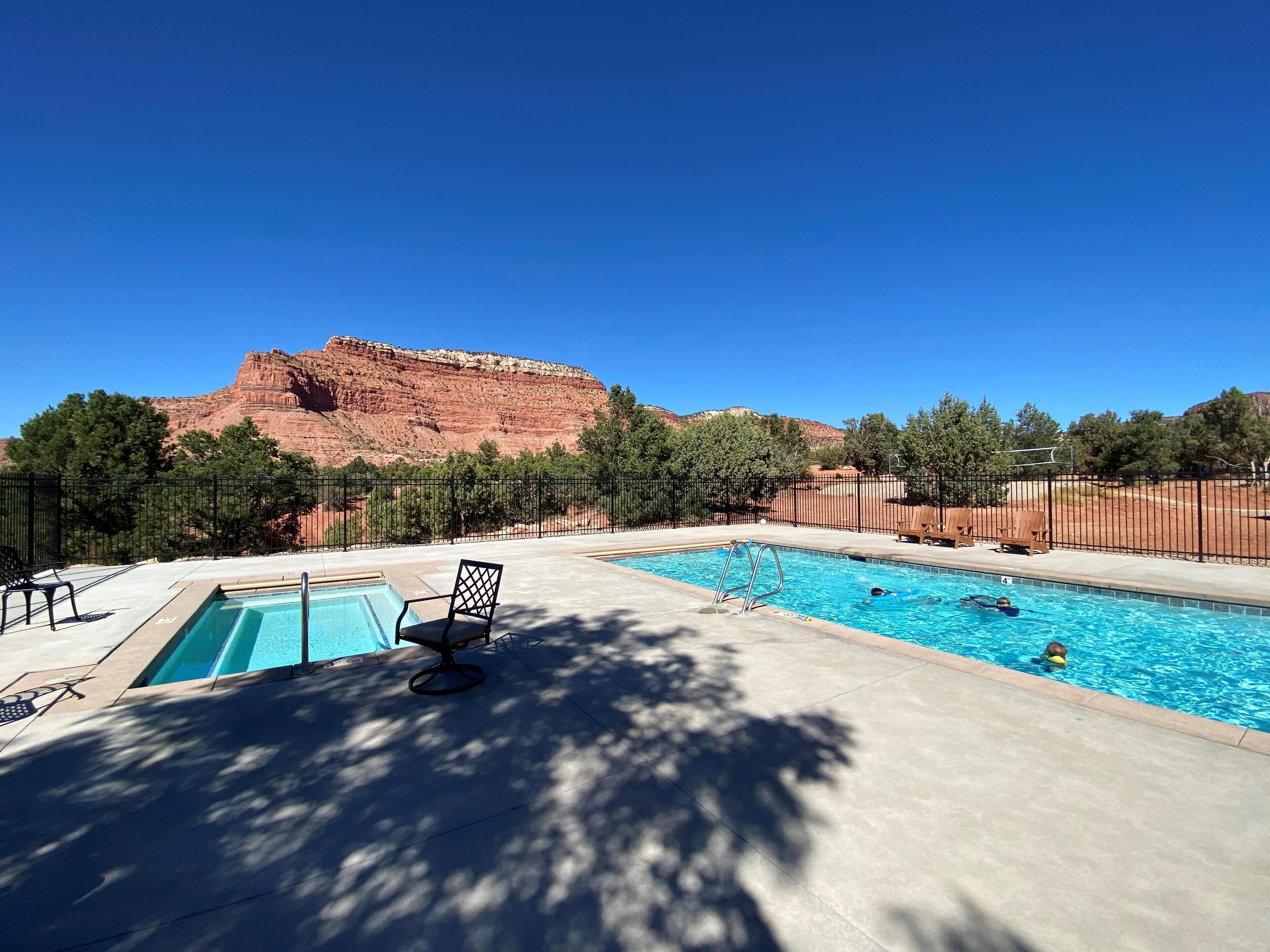 A swimming pool with a view of red rock formations and trees.