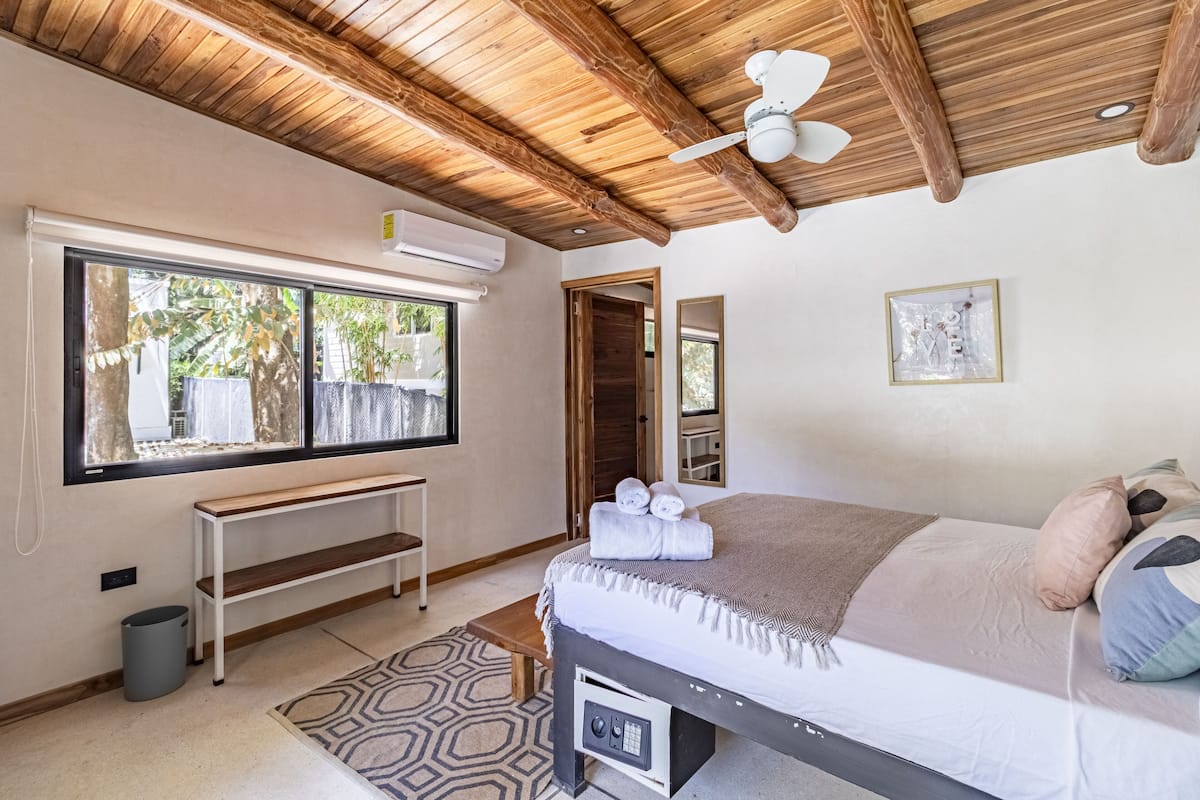 Une chambre avec un plafond en bois, un lit avec des serviettes, un banc, une fenêtre et un miroir.