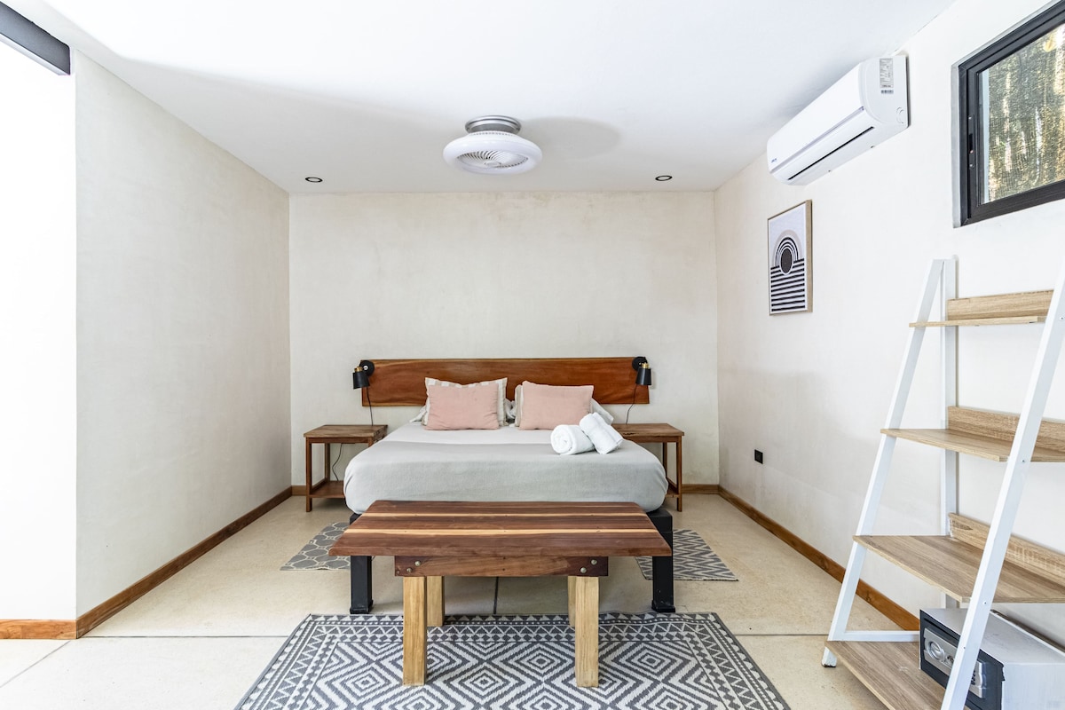 A bedroom with a bed, bedside tables, a bench, a wall-mounted shelf, and a ceiling fan.