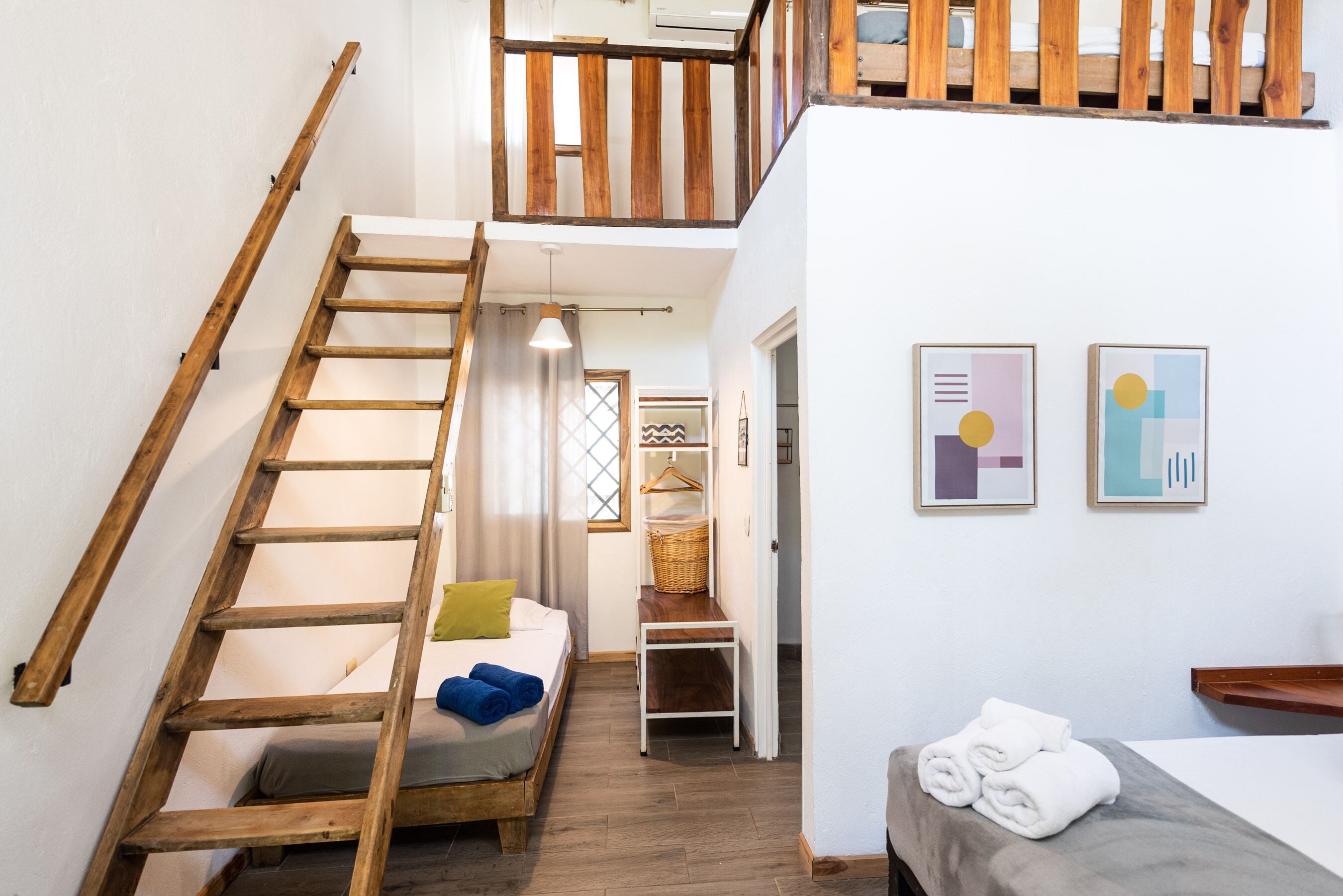 Ein Schlafzimmer im Loft-Stil mit einer Holzleiter, einem Bett mit Kissen, einem kleinen Tisch und einer Bank.