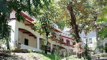 Un edificio con techo de tejas rojas y paredes blancas, rodeado de follaje y árboles.