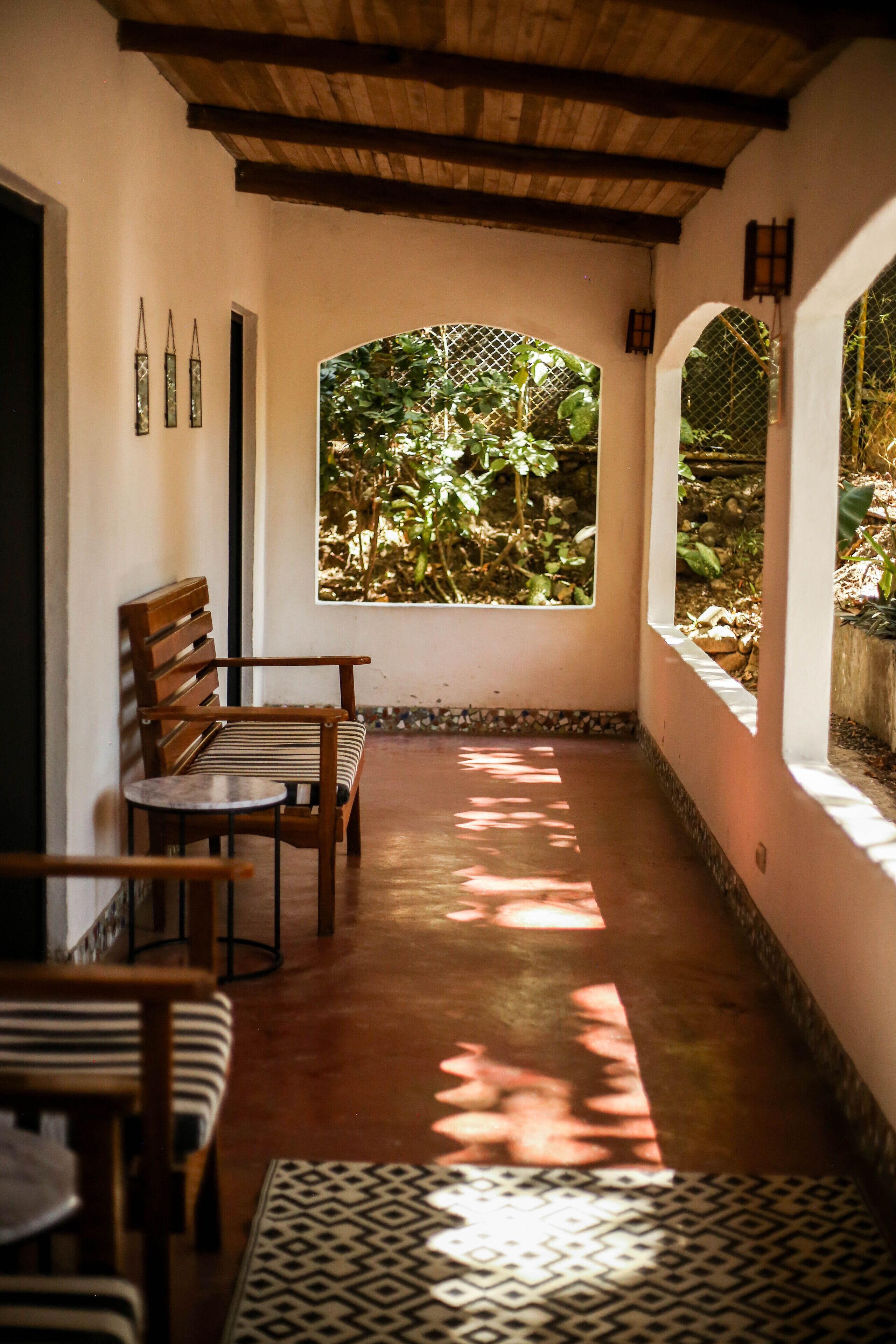 A corridor with a wooden bench, a patterned rug, and a window with a view of greenery.
