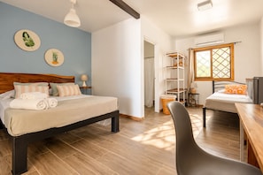 Een slaapkamer met een bed, nachtkastje, lamp en een raam met uitzicht.