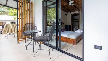 Une pièce comprenant un lit, une table et une chaise, avec vue sur l’extérieur grâce à une porte vitrée.