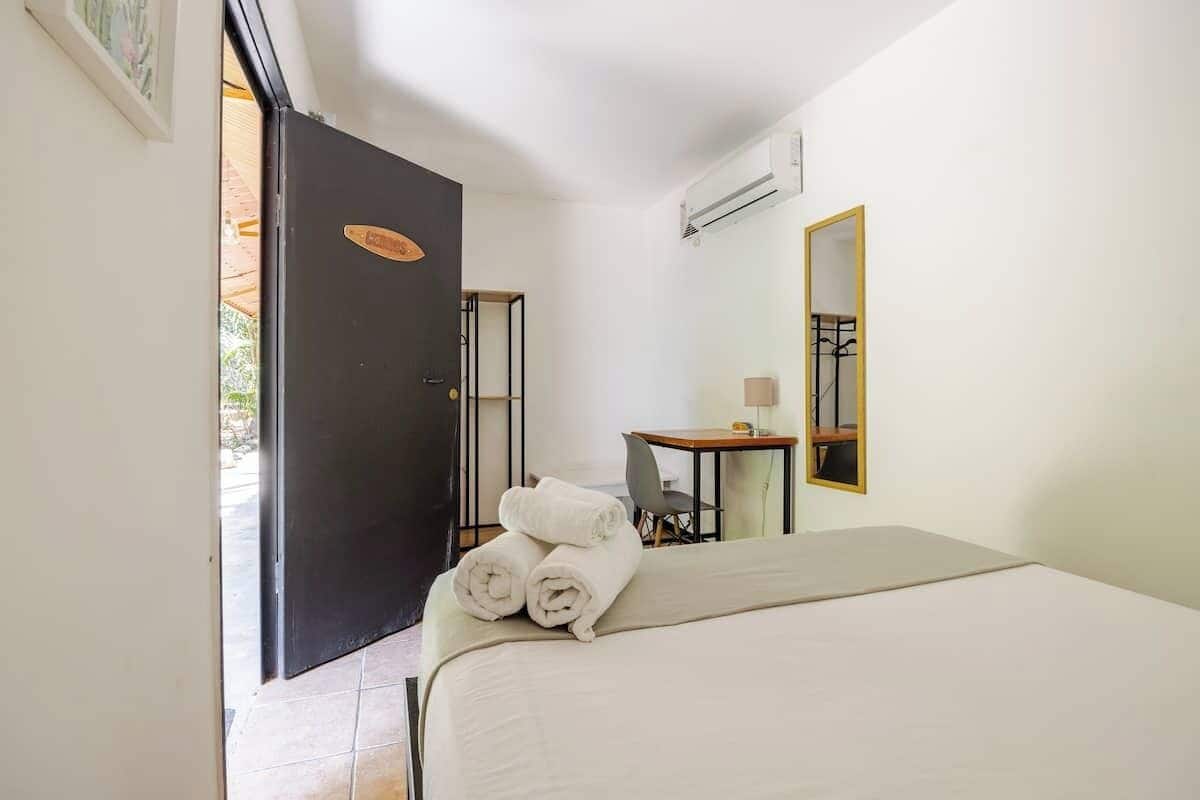Une chambre d’hôtel équipée d’un lit, d’un bureau, d’une chaise, d’un miroir et d’un appareil de climatisation.