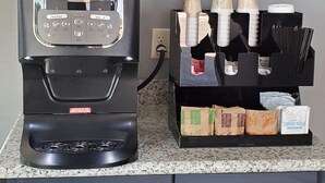 A Nescafe coffee machine on a countertop with a coffee cup and saucer, a coffee grinder, and a coffee pod holder. - Crescent Park Motel & Suites (Littlefield)