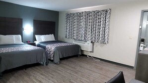 A hotel room with two beds, a desk, a chair, and a window with patterned curtains. - Crescent Park Motel & Suites (Littlefield)