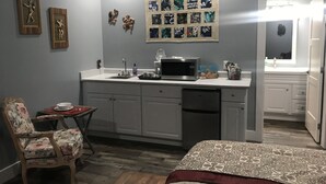 Una habitación compacta con cama, un pequeño escritorio con microondas y una silla.