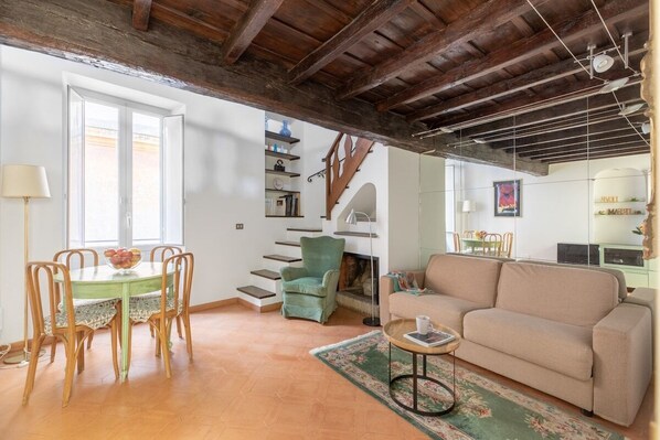 A spacious living area with a dining table, sofa, and staircase leading to an upper floor.