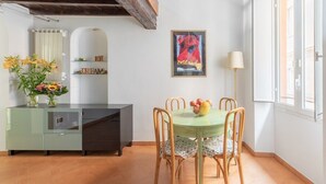 A dining area with a green table and chairs, a vase of flowers, and a framed picture on the wall. - Joy Apartment 2 - Rome - Trastevere (Roma)