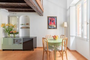 Un comedor con una mesa y sillas verdes, un jarrón de flores y un cuadro en la pared.
