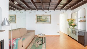 A living room with a sofa, a small round table, a mirror, and a cabinet. - Joy Apartment 2 - Rome - Trastevere (Roma)