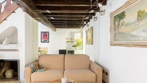 A living room with a beige sofa, a small wooden coffee table, a fireplace, and a painting on the wall. - Joy Apartment 2 - Rome - Trastevere (Roma)