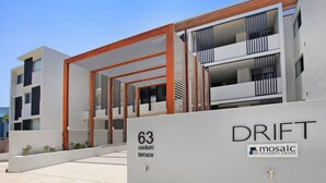 A modern apartment building with balconies and a covered terrace.