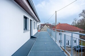 A narrow, covered walkway leading to a building with a red-tiled roof.
