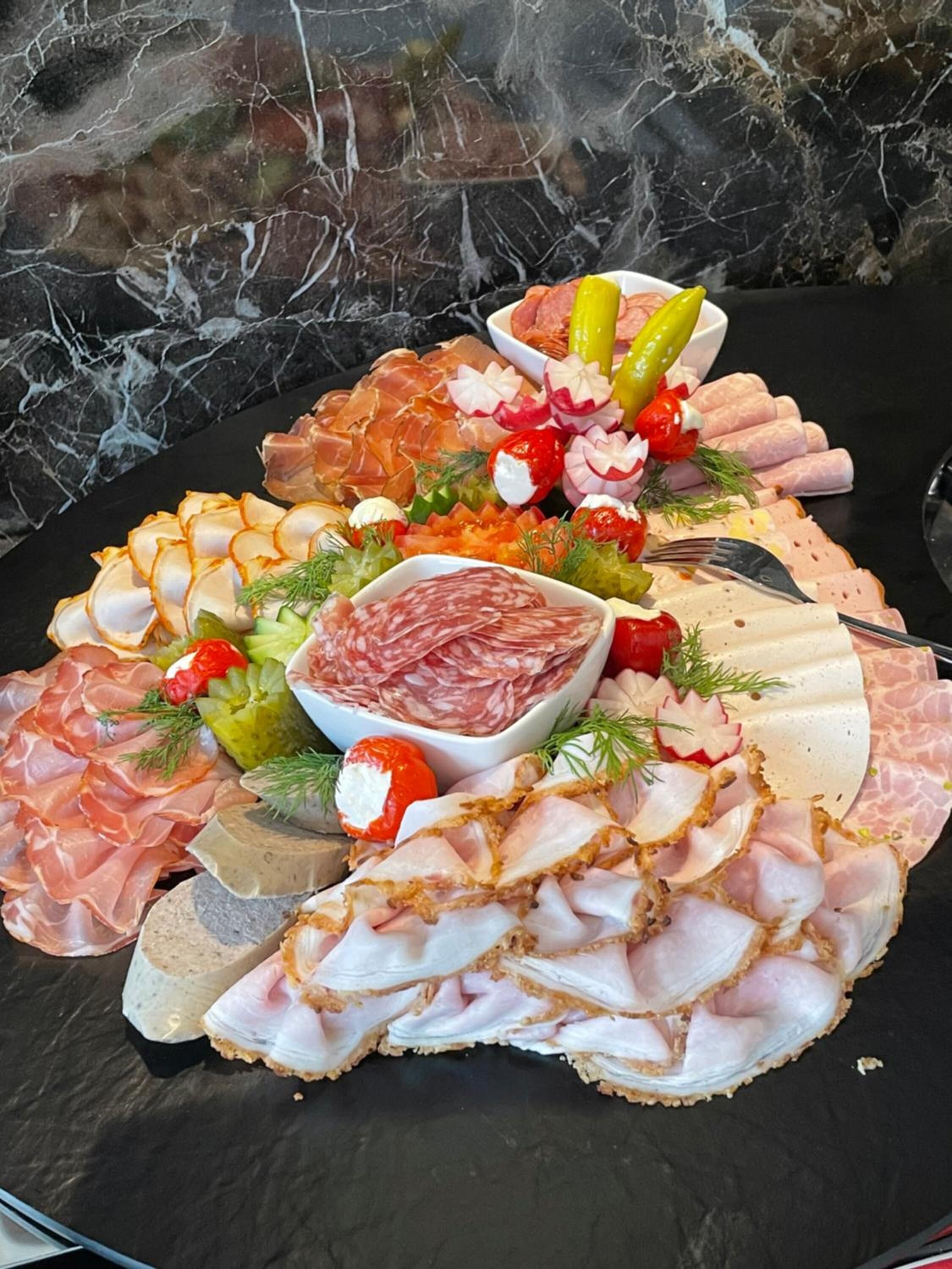 Una tabla de embutidos con diversos quesos y adornos.