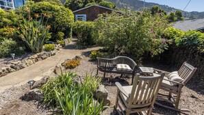 Un jardin avec un banc en bois, une petite table et une maison en arrière-plan.
