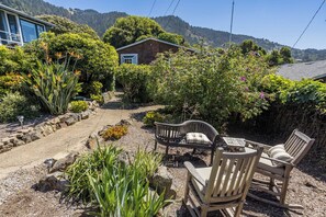 A garden with a wooden bench, a small table, and a house in the background.