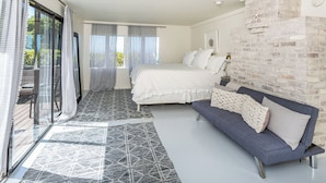 Une chambre avec un lit, un canapé, un mur en briques et une vue à travers une porte vitrée.