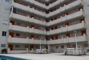 Un edificio de varios pisos con zona de piscina.