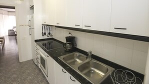 Eine moderne Küche mit weißen Schränken, einer schwarzen Arbeitsplatte, einem eingebauten Backofen und einem Edelstahl-Spülbecken.